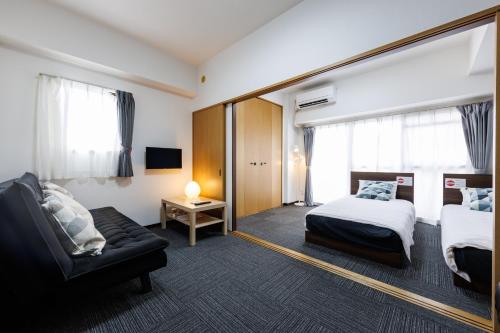 a hotel room with a bed and a couch at Grande Famille Shimanouchi Dotonbori Condo in Osaka