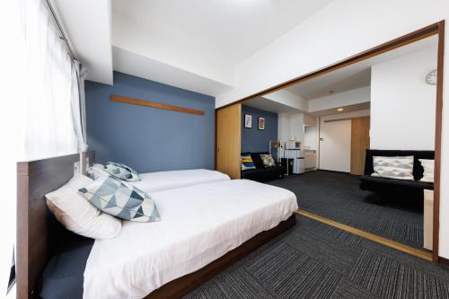 a bedroom with a large white bed and blue walls at Grande Famille Shimanouchi Dotonbori Condo in Osaka