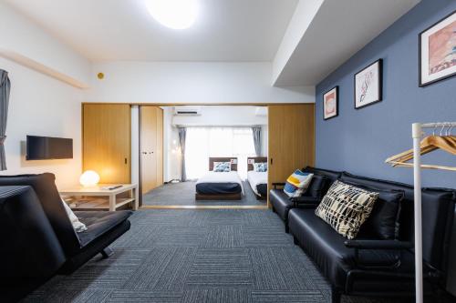 a living room with a couch and a bed at Grande Famille Shimanouchi Dotonbori Condo in Osaka