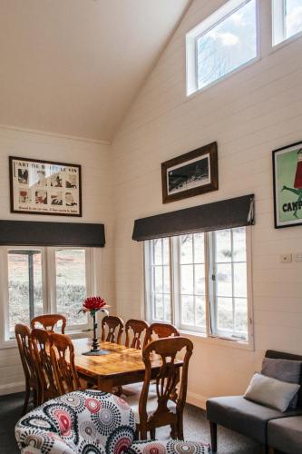 a dining room with a table and chairs and windows at Crackenback Farm Guesthouse in Crackenback