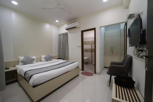 a bedroom with a bed and a television and a chair at Hari Haran Prestige in Varanasi