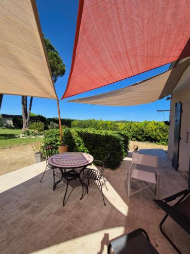 a patio with a table and chairs under an umbrella at Maison familiale avec Mazet et grande piscine Uzès in Uzès