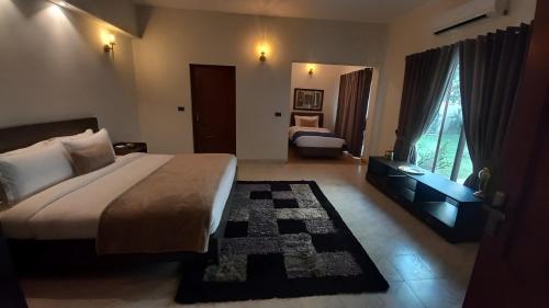 a bedroom with a bed and a desk and a room with two beds at CHK INN by ChenOne in Lahore