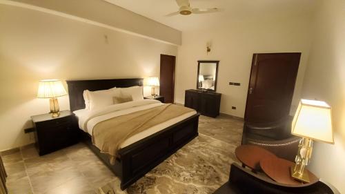 a bedroom with a bed and two lamps and a chair at CHK INN by ChenOne in Lahore