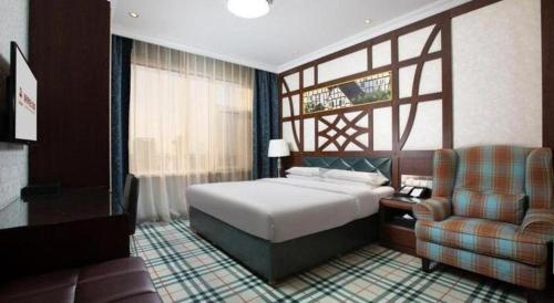 a hotel room with a bed and a chair at Zaozhuang Hotel in Zaozhuang