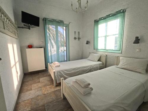 ein Schlafzimmer mit zwei Betten und einem Fernseher und einem Fenster in der Unterkunft Crisio Studios in Skyros