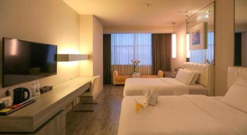 a hotel room with two beds and a flat screen tv at Jinjiang Metropolo Hotel - Qingdao Chengyang District Government in Qingdao