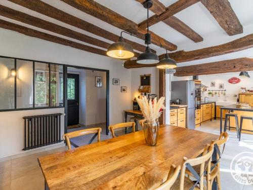 une cuisine et une salle à manger avec une table et des chaises en bois dans l'établissement Gîte de Charme en Campagne - Confort & Luxe - FR-1-622-110, à Chazé-sur-Argos