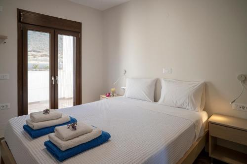 une chambre avec un lit blanc avec des serviettes dessus dans l'établissement Kavo Plako Studio 1, à Palekastro