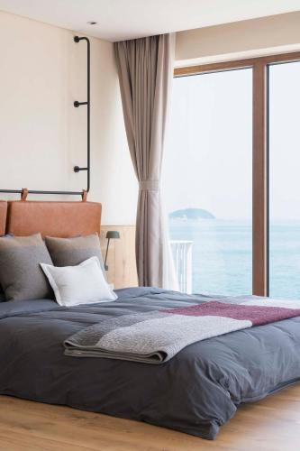 a bedroom with a bed with a large window at 朴宿栖澜海居崂山风景区店 in Qingdao