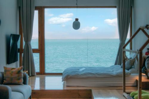a bedroom with a view of the ocean through a large window at 朴宿栖澜海居崂山风景区店 in Qingdao