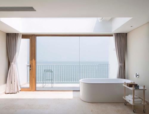 a bath tub in a bathroom with a large window at 朴宿栖澜海居崂山风景区店 in Qingdao
