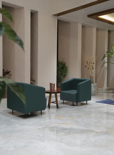 two green couches in a lobby with a table at Gir Aatithya Clarks Inn in Sasan Gir