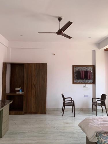 ein Wohnzimmer mit 2 Stühlen und einem Deckenventilator in der Unterkunft Jai mewar continental in Udaipur