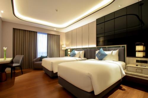 a hotel room with two beds and a desk at FUGO Hotel Banjarmasin in Banjarmasin