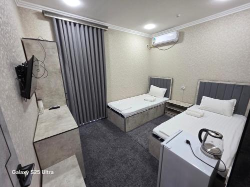 ナボイにあるAnor Hotel Navoiyのベッド2台とテレビが備わる小さな客室です。