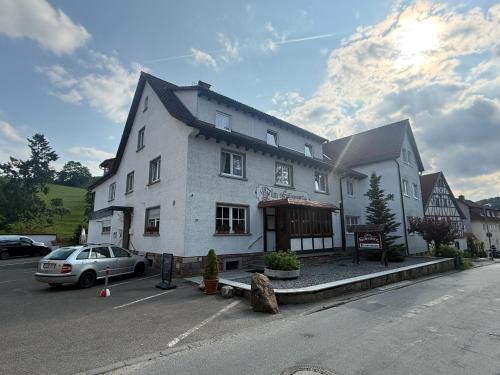 a white building with a car parked in a parking lot at Zum Kaiserwirt in Heppenheim an der Bergstrasse