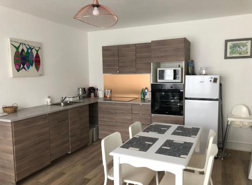 une cuisine avec une table et un réfrigérateur blanc dans l'établissement Appartement Lumineux-Coeur de ville & plages, à Concarneau