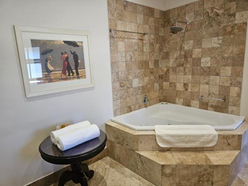 L'Heritage Retreat في Wildernis: حمام مع حوض استحمام مع صورة على الحائط