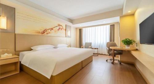 a hotel room with a large bed and a television at Vienna Hotel Harbin Central Avenue in Harbin