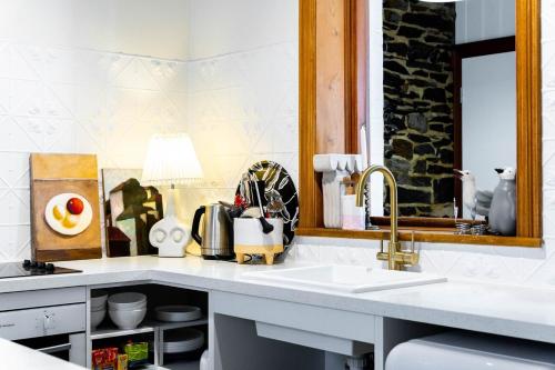 a kitchen counter with a sink and a mirror at Coachman's Cottage Glenelg in Glenelg