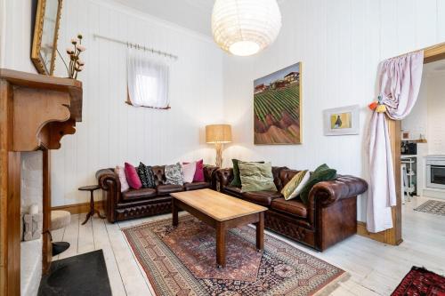a living room with leather couches and a table at Coachman's Cottage Glenelg in Glenelg