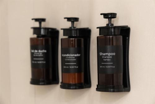 a group of three bottles of shampoo on a wall at Dazzler by Wyndham Montevideo in Montevideo