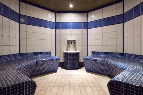 a bathroom with blue and white tiled walls and benches at Lindner Hotel Leverkusen BayArena, part of JdV by Hyatt in Leverkusen