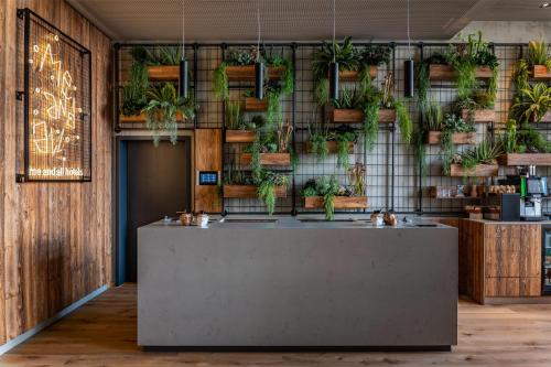 a room with a reception counter with potted plants at Me and All Hotel ulm, by Hyatt in Ulm
