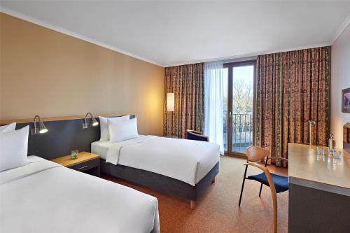 a hotel room with two beds and a desk at Lindner Hotel Leverkusen BayArena, part of JdV by Hyatt in Leverkusen