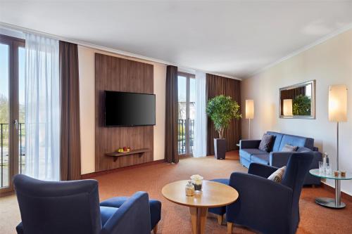 a living room with a couch and a tv at Lindner Hotel Leverkusen BayArena, part of JdV by Hyatt in Leverkusen