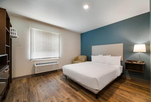a bedroom with a white bed and a blue wall at WoodSpring Suites Cocoa Beach - Rockledge in Rockledge