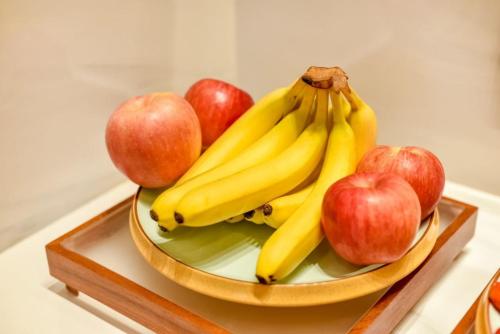 a bowl of bananas and apples on a table at Atour Light Hotel Beijing West Station Maliandao in Beijing