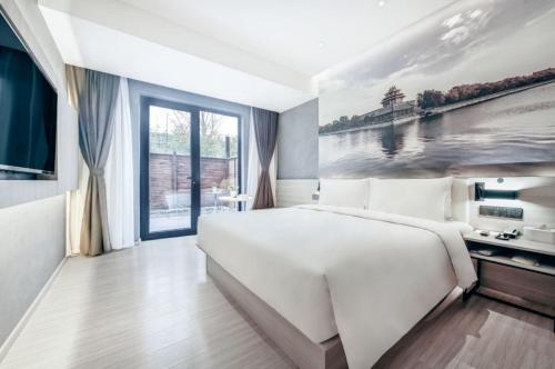a bedroom with a large white bed and a painting at Atour Light Hotel Beijing West Station Maliandao in Beijing