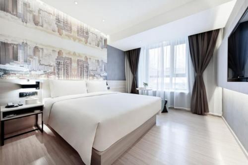 a bedroom with a large white bed and a television at Atour Light Hotel Beijing West Station Maliandao in Beijing