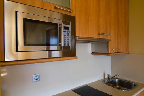 a kitchen with a stainless steel microwave and a sink at Apartamentos Esperanza del Mar in Portonovo
