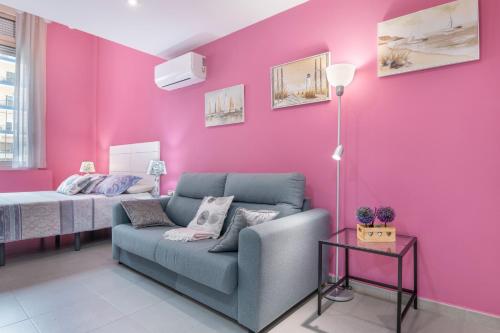 ein Wohnzimmer mit einer Couch und einer rosa Wand in der Unterkunft Estudio Arena, A Pie De Playa in Cádiz