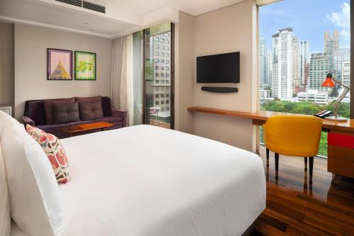 a hotel room with a bed and a desk and a window at Hotel Indigo Bangkok Wireless Road by IHG in Bangkok