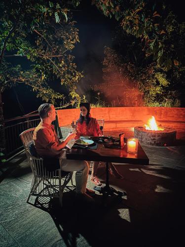 a man and woman sitting at a table in front of a fire at Kandy Dendrobium House in Kandy