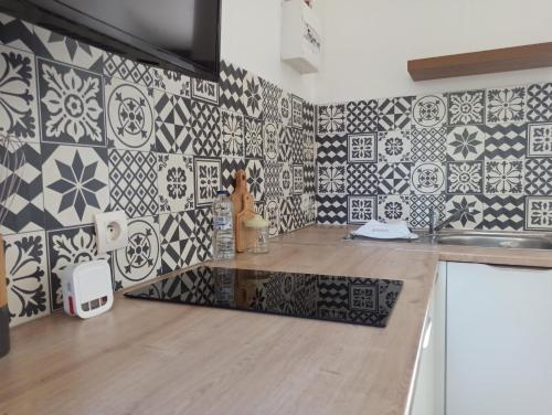 - une cuisine avec du carrelage noir et blanc sur le mur dans l'établissement Studio cosy, à Sorgues