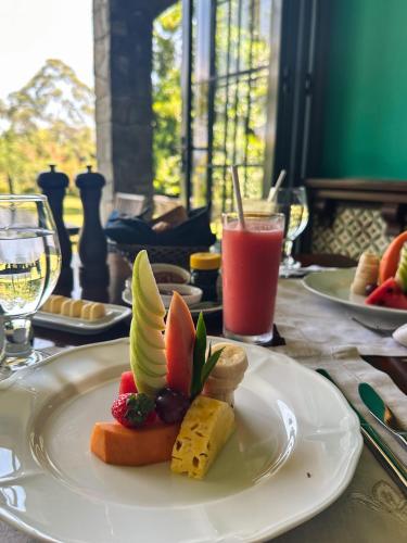 a plate of food with fruit and cheese on a table at Kandy Dendrobium House in Kandy