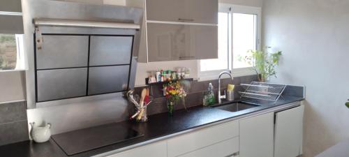 une cuisine avec un évier et un plan de travail noir dans l'établissement Maison dans le sud au calme avec extérieur, à Ferrals-lès-Corbières