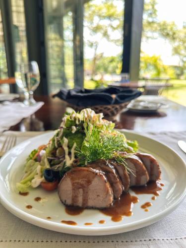 a plate of food with meat and salad on a table at Kandy Dendrobium House in Kandy
