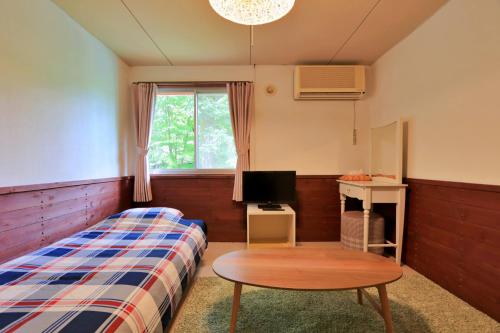 a bedroom with a bed and a table and a tv at Pension Asuka inn Daisen in Hoki