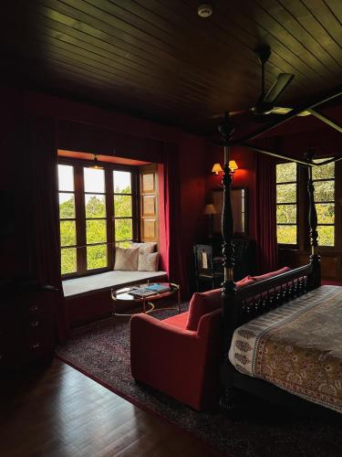 a bedroom with a bed and a couch and windows at Kandy Dendrobium House in Kandy