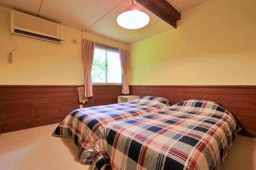 a bedroom with a bed with a plaid blanket at Pension Asuka inn Daisen in Hoki