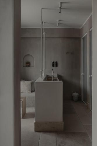 a white bathroom with a sink and a bed at Akria Seaside Suites in Naousa