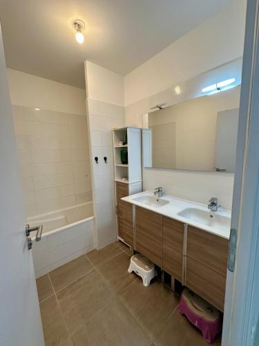 une salle de bain avec deux lavabos et une baignoire dans l'établissement Maison proche plage, à Villeneuve-lès-Maguelone