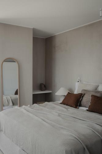 a white bedroom with a large bed and a mirror at Akria Seaside Suites in Naousa