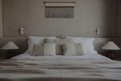 a bedroom with a bed with pillows and two lamps at Akria Seaside Suites in Naousa